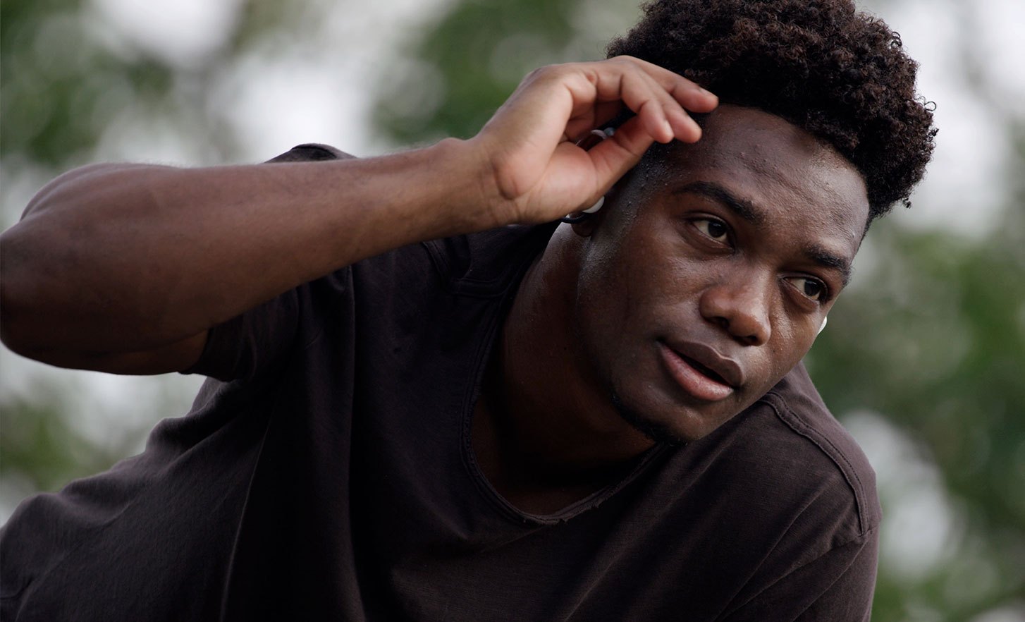 Image of a man outdoors touching his forehead and wearing Sony Float Run headphones